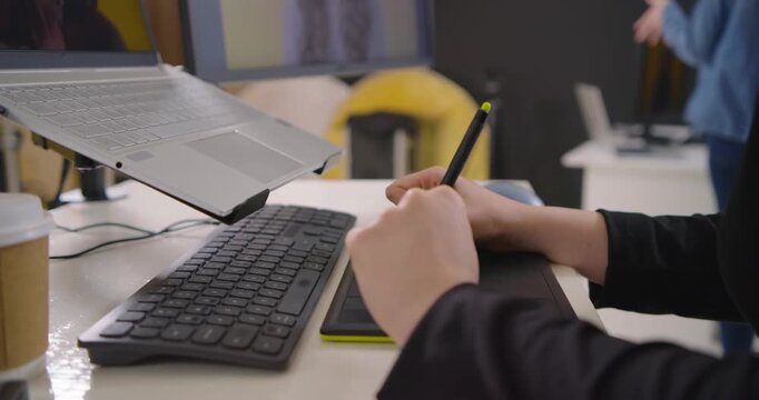 Female duo, designer using stylus tablet reviewing edits after peer pointing in studio, copy space