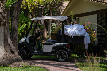 Electric utility golf cart transporting white linens at a resort © Nataliia