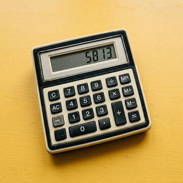 Old School Calculator Displaying Numbers 5813 on Yellow Tabletop Business and Finance Concept