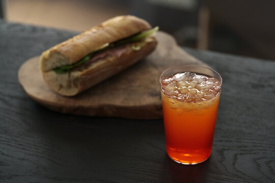 orange lemonade with baguette sandwich on background on black wood table