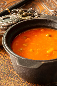 Bowl of vegetable soup with a vintage leather journal, fountain pen and a pocket fob watch on an aged leather background backdrop