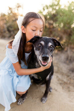 Young girl kisses her happy senior mixed breed dog