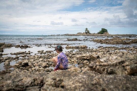 Young child exploring tide pools on a rocky beach