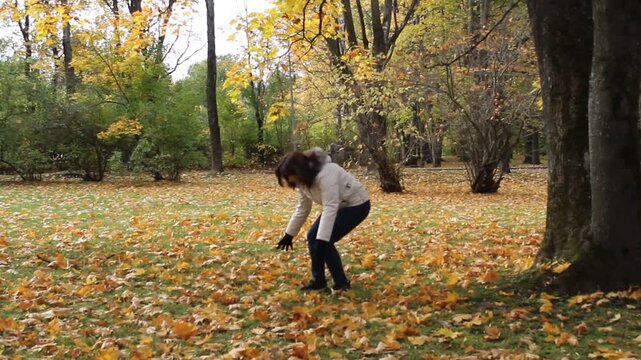 Happy Woman Throwing Autumn Leaves in Forest.

