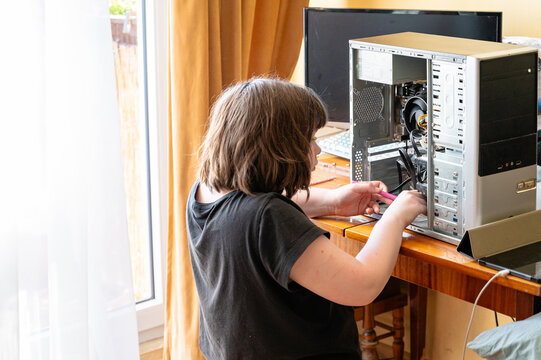 Focused teenage girl assembling hardware components inside a computer case