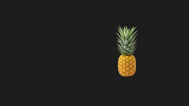 Fresh whole pineapple sliding across a black background