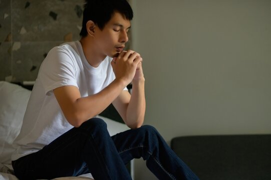 Thoughtful Young Man in Casual Clothing Sitting on a Bed