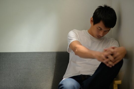 Young Man in Casual Wear Expressing Sadness and Reflection in Room