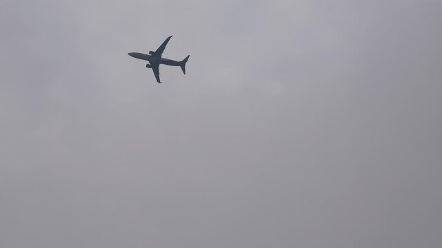 Commercial passenger airplane flying high through dramatic cloudy sky during daytime, aviation stock footage
