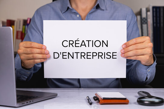 Une personne en chemise tenant une feuille de papier sur laquelle est &eacute;crit en gros les mots cr&eacute;ation d'entreprise.