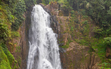 Powerful Haew Narok waterfall in Khao Yai National Park.A majestic view of Haew Narok waterfall cascading down a steep rocky cliff surrounded by lush green tropical jungle in Thailand. © tonyram2