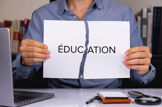 Une personne en chemise tenant une feuille de papier d&eacute;chir&eacute;e sur laquelle est &eacute;crit en gros le mot &eacute;ducation.