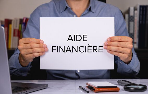 Une personne en chemise tenant une feuille de papier sur laquelle est &eacute;crit en gros les mots mots aide financi&egrave;re.