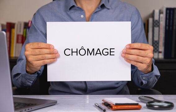 Une personne en chemise tenant une feuille de papier sur laquelle est &eacute;crit en gros le mot ch&ocirc;mage.