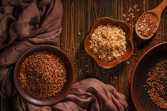 Rural still life with top view of the buckwheat flakes and the peeled groats of buckwheat, on a wooden surface closeup