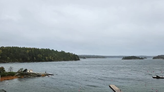 Beautiful view of rainy Baltic Sea with docks and buoys against background of rocky forested islands. Sweden.