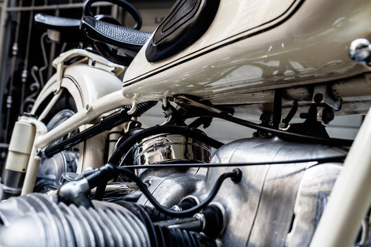 Illustrative editorial close up shot of a classic vintage BMW motorcycle boxer engine and fuel tank with pinstripes parked outdoors reflecting engineering heritage.