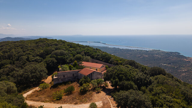 Breathtaking landscape vista of a prominent ancient monastery on a lush green mountain peak with the vast Korission Lagoon in the background
