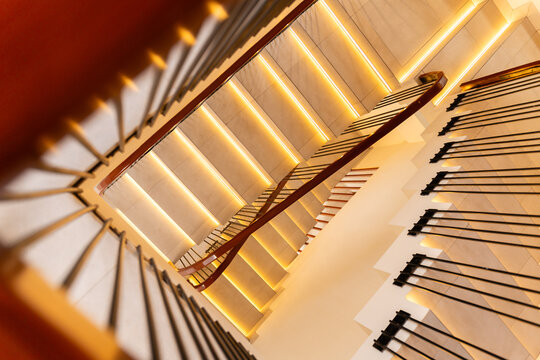 High angle perspective of minimalist wooden steps with integrated golden LED lighting, contemporary interior design.