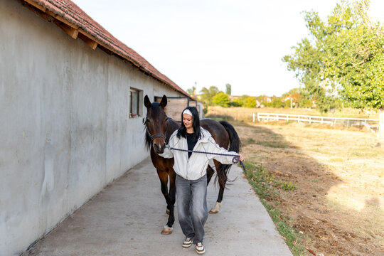 A young, dark haired woman prepares her horse for a ride at dusk on an autumn day. She grooms him, kisses him, and whispers to him, showing him how much she loves him.
