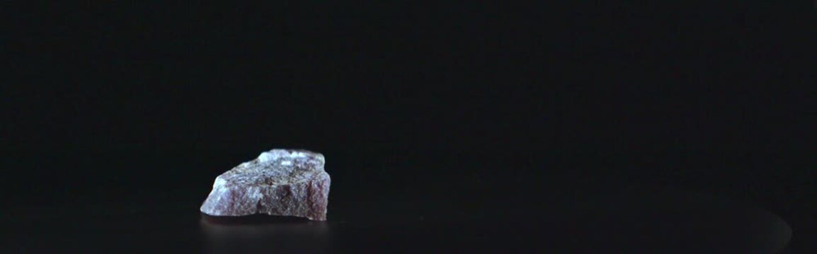 Cinematic close up of purple lepidolite mineral on black background