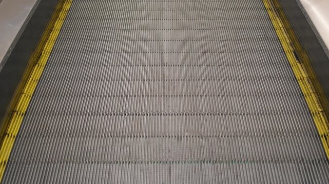Close-up of a moving walkway or travelator with yellow safety lines inside a modern shopping mall or supermarket. Retail trade, commerce and modern infrastructure concept.