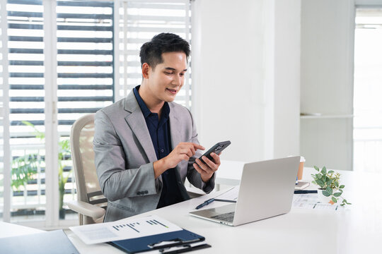 Business manager ceo using cell phone mobile app. Young  businessman holding smartphone sitting in office working online on gadget.