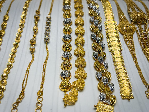 Gold chains and bracelets laid out on a white background in the gold souk of Deira, Dubai, United Arab Emirates