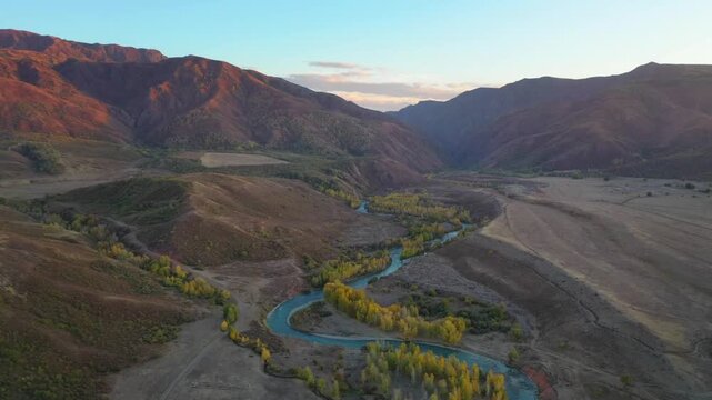 Aerial view of Tentek river bends winding through autumn valley in Dzungarian Alatau, Kazakhstan. Ideal for travel layouts, environmental concepts, and nature backgrounds with copy space.