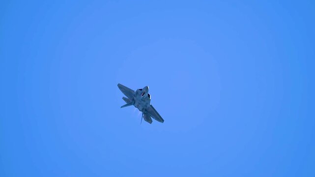 An F-22 Raptor Stealth Fighter Jet Climbing Upward Against a Deep Blue Sky Backdrop.