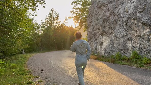  Pedestrian talking on smartphone while walking along empty mountain road by cliff at sunset &mdash; travel, mobile connection