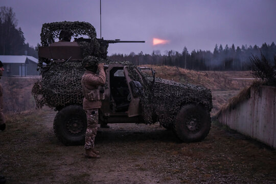 Machine gun firing from a French military vehicle at dusk during multinational training in Tapa, Estonia