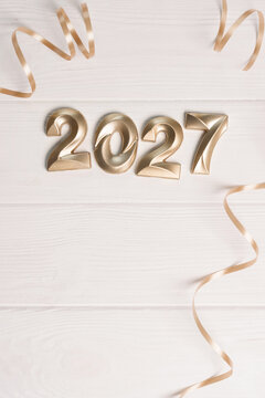 Golden vertical numbers 2027 and decorative ribbons creating a cheerful festive for upcoming events atmosphere