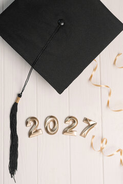 Graduation cap with 2027 numbers and golden ribbon symbolizing academic future success achievement vertical