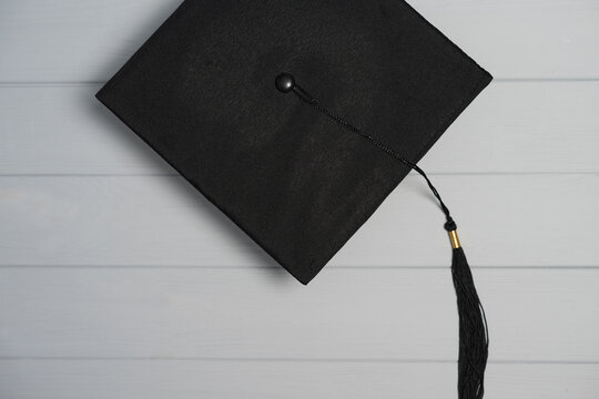 Black graduation cap with tassel symbolizing education learning and accomplishment on a light wood background