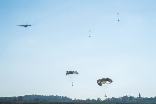 Transport aircraft turning away as parachute canopies open during a joint airborne exercise over Caylus, France