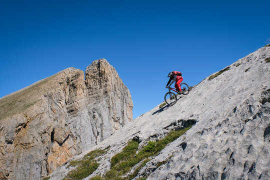 Mountain biker commits to a limestone slab off trail in the high Pyrenees, Aragnouet, France