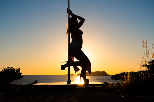 Female Pole Dancer silhouette performing in Ibiza sunset