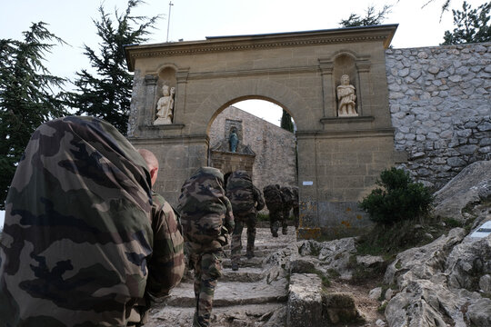 Column of Foreign Legion recruits climbing steps through an old gate during a march in France