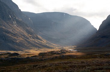 Golden hour landscape along the Kungsleden in Swedish Lappland, with a stunning valley framed by mountains with sunbeams pouring in © Jacob Hall