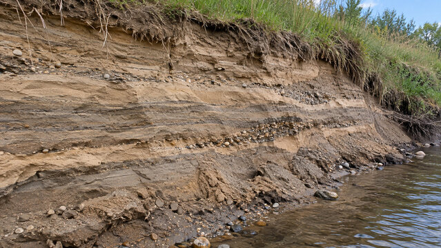 Exposed sediment layers and gravel lenses beside a river