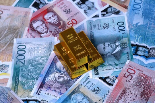 Jamaican dollar money bills and gold bullion bars. Jamaica cash bills of JMD currency close up
