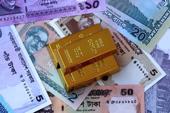 Bangladeshi taka money bills and gold bullion bars. Bangladesh cash bills of BDT currency close up