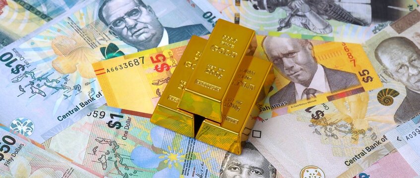 Bahamian dollar money bills and gold bullion bars. Bahamas cash bills of BSD currency close up