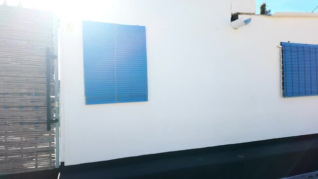 Sunlit white wall with blue window shutters