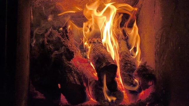 Fire burning on wood inside fireplace, fire producing heat and bright flame dark interior. Glowing coal and ember forming warm atmosphere, natural energy concept, closeup detail, background, winter