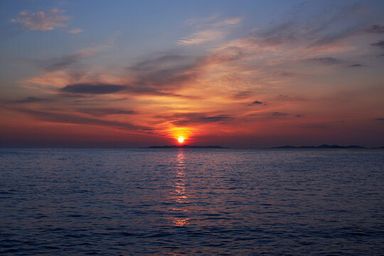 Sunset or sunrise over the sea, Seascape with ocean, cloudy sky and small islands far away.