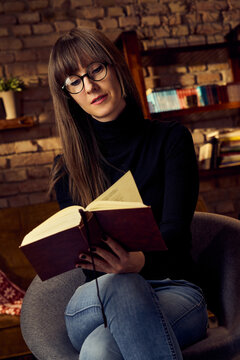 young 30s woman reading a book at home relaxing.