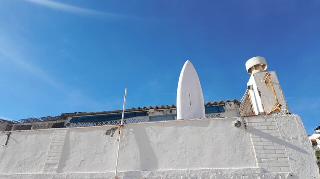 Satellite dish on a white rooftop under blue sky