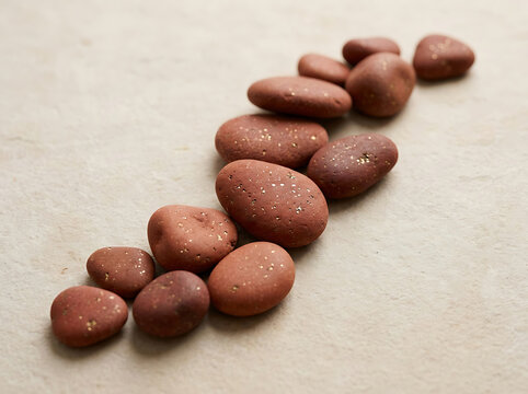 Smooth red pebbles arranged in a curved line on a textured beige